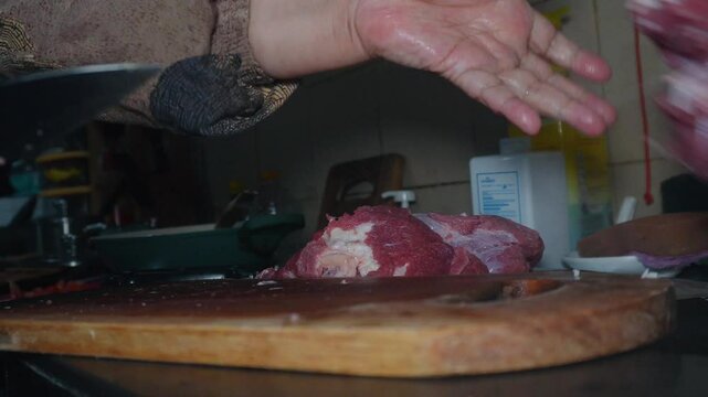 chopping raw beef meat on a chopping board. The meat is raw and has a lot of fat. Cooking preparation in the kitchen