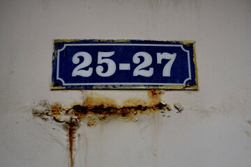 Numéros 25-27. Plaque de numéro de rue sur mur blanc.