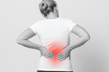 Woman holding her lower back in pain with a red highlighted area.