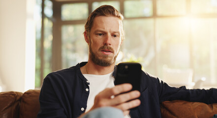 Confused, phone and worry with man on sofa for phishing email, fake news and thinking. Virus warning, password leak and scam alert with person and mobile in living room of home for hacker threat © LuxeShutter24/peopleimages.com