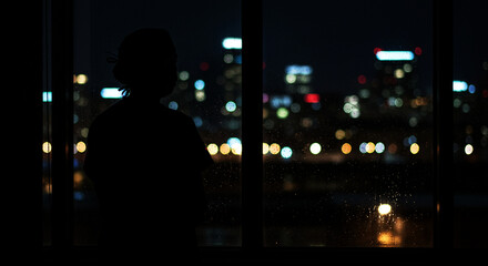 a healthcare professional's silhouette standing by a hospital window at night