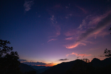 Milky Way above mountains at night in autumn. Landscape with mountain valley, low clouds, purple starry sky with milky way. The Milky Way shines on a cold night in the north of Thailand