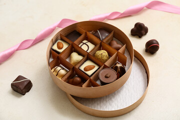 Box with delicious chocolate candies and ribbon on white grunge background