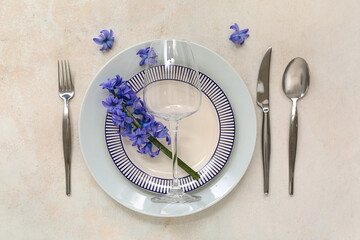 Beautiful table setting with plates, cutlery, wine glass and flowers on light background