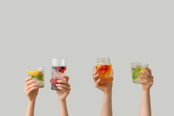 Many hands with infused water on light background