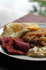 Close-up of a gallo pinto, a typical Costa Rican dish with rice, red beans, sausage, cream, and a fried egg.