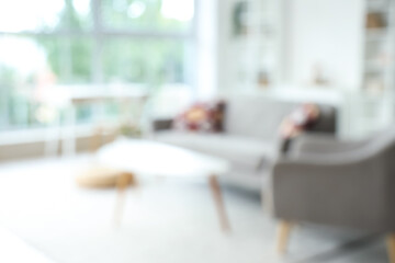 Blurred view of living room with grey sofa, armchair and tables