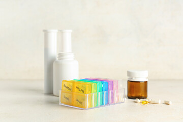Pack of plastic pill organizers and bottles on table against white background