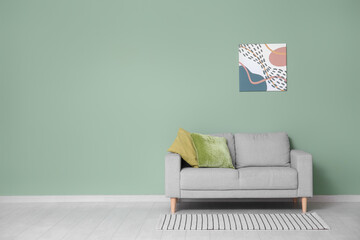 Sofa with cushion and picture on green wall in room