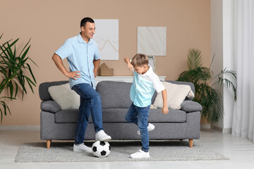Happy father with his little son playing football at home
