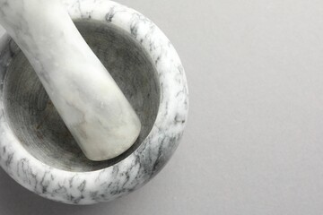 Marble mortar and pestle on light grey background, top view. Space for text