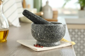 Stone mortar, pestle and spices on wooden table in kitchen