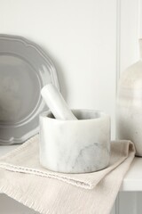 Marble mortar and pestle on white table indoors, closeup