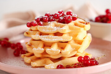 Delicious Belgian waffles with redcurrant and powdered sugar on plate on table against white background. Closeup