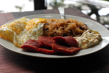 Close-up of a gallo pinto, a typical Costa Rican dish with rice, red beans, sausage, cream, and a fried egg.