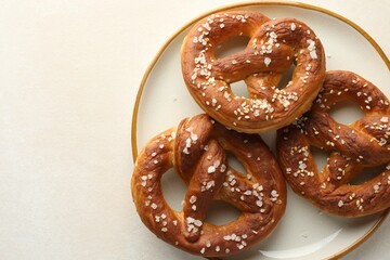 Tasty pretzels with salt on white table, top view. Space for text
