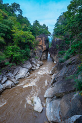 The beautiful scenery of the river valley surrounded by lush green forest, with towering rock formations like kissing cliffs and narrow bridges connecting the cliffs. Amazing kissing cliffs on river