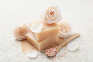 Soap bars, sea salt and flowers on white textured table, closeup