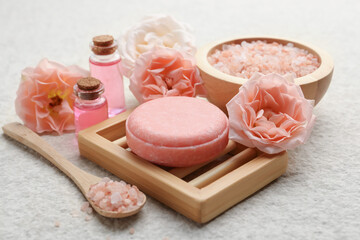Soap bar, sea salt, essential oils and beautiful roses on beige table, closeup