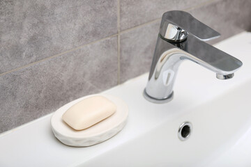 Soap bar near faucet on sink in bathroom, closeup