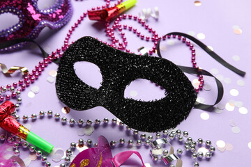 Beautiful carnival masks with party horns, confetti and beads on lilac background