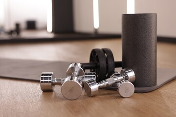 Dumbbells, ab roller and mat on floor in fitness studio