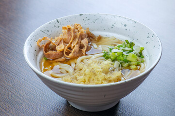 A bowl of udon noodles with a large tempura prawn.