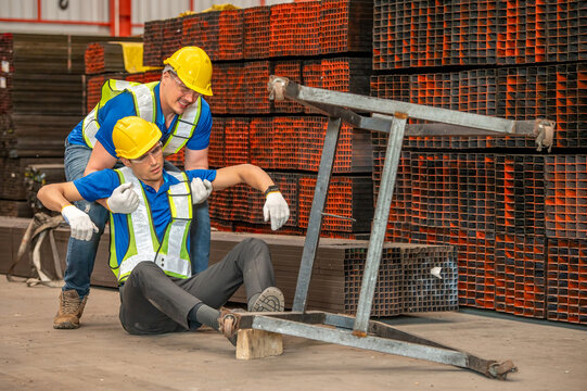 A worker fell and injured his leg at a construction site. Another worker is helping him. - Powered by Adobe