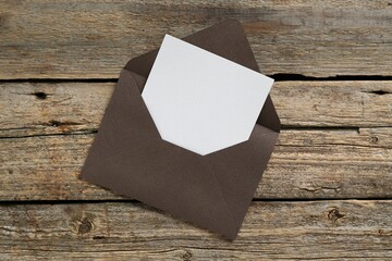 Blank invitation card and envelope on wooden table, top view. Space for design