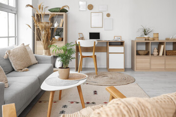 Stylish interior of living room with soft sofa, workplace and armchair