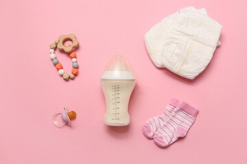 Bottle with milk for baby and accessories on pink background