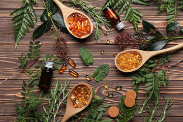 Composition with different pills and fresh herbs on wooden background