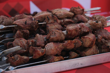 Ready pork shashlik on skewers cools on an iron tray. Appetizing street food, freshly cooked juicy meat at a city festival