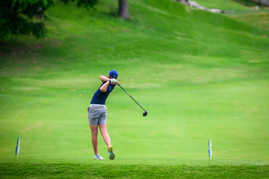 Male Golfer Swinging Driver on Lush Green Tee Box