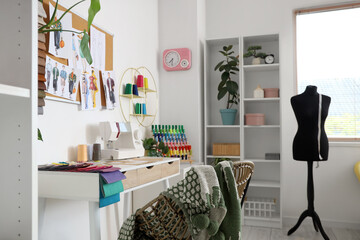 Interior of light atelier with tailor's workplace, shelf unit and mannequin