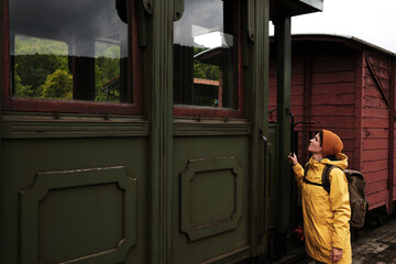 Woman in yellow raincoat exploring historic green railway carriage at Shargan - Sargan railway...