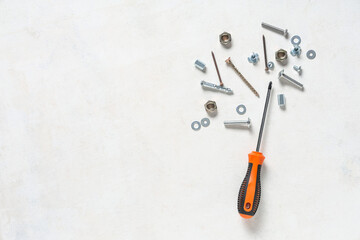 Screwdriver with tap bolts, screws and chrome nuts on white grunge background