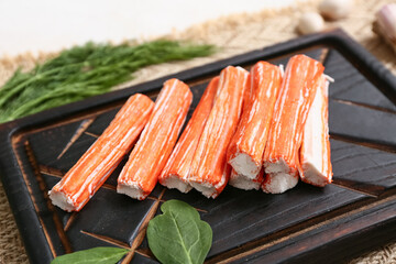 Wooden board with tasty crab sticks, spinach leaves and dill on white background, closeup