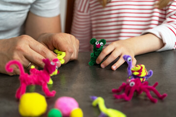 Close up of fathers and childs hands make diy from colored chenille wire toys. Family create...