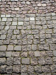 Vertical stone granite background with old sidewalk. The surface is paved with multi-colored granite blocks. Copy space.