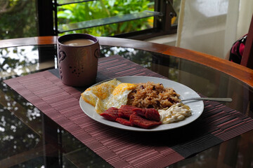 Gallo pinto, a typical Costa Rican dish with rice, red beans, sausage, cream, and a fried egg, and...