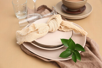 Beautiful table setting with fresh green leaves on beige wooden background