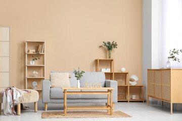 Sofa, table and vases with eucalyptus branches in interior of living room
