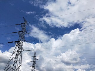 High voltage power lines and towers against blue sky with clouds