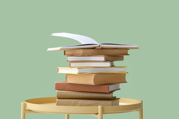 Stack of books on coffee table near green wall, closeup