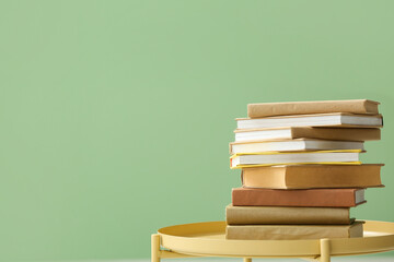 Stack of books on coffee table near green wall, closeup