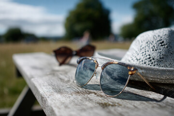 Gafas de sol sobre una superficie en día soleado, con fondo natural desenfocado.