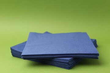 Stack of blue handkerchiefs on green background, closeup. Space for text