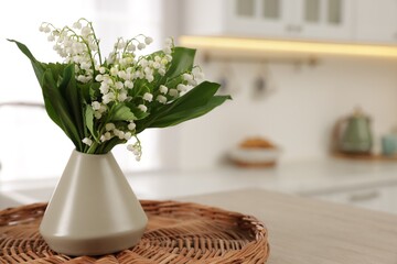 Bouquet of beautiful lily-of-the-valley in vase on table in kitchen, closeup. Space for text