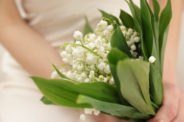 Obraz premium Woman with beautiful lilies of the valley flowers indoors, closeup
